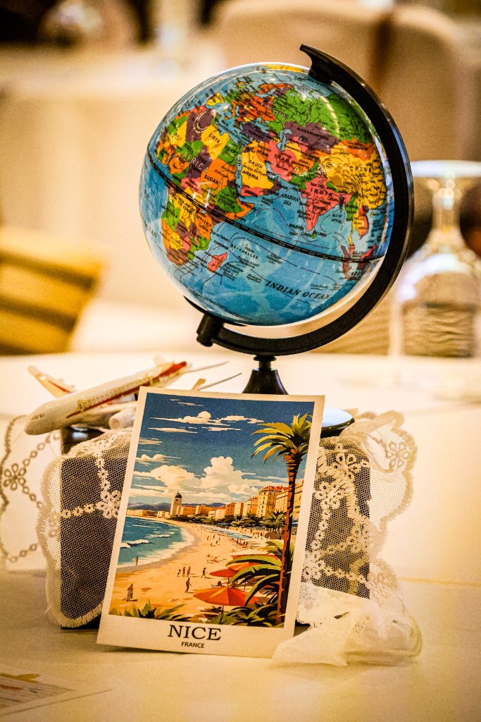 Vintage Nice France postcard centerpiece with spinning globe and model airplane on lace doily at event