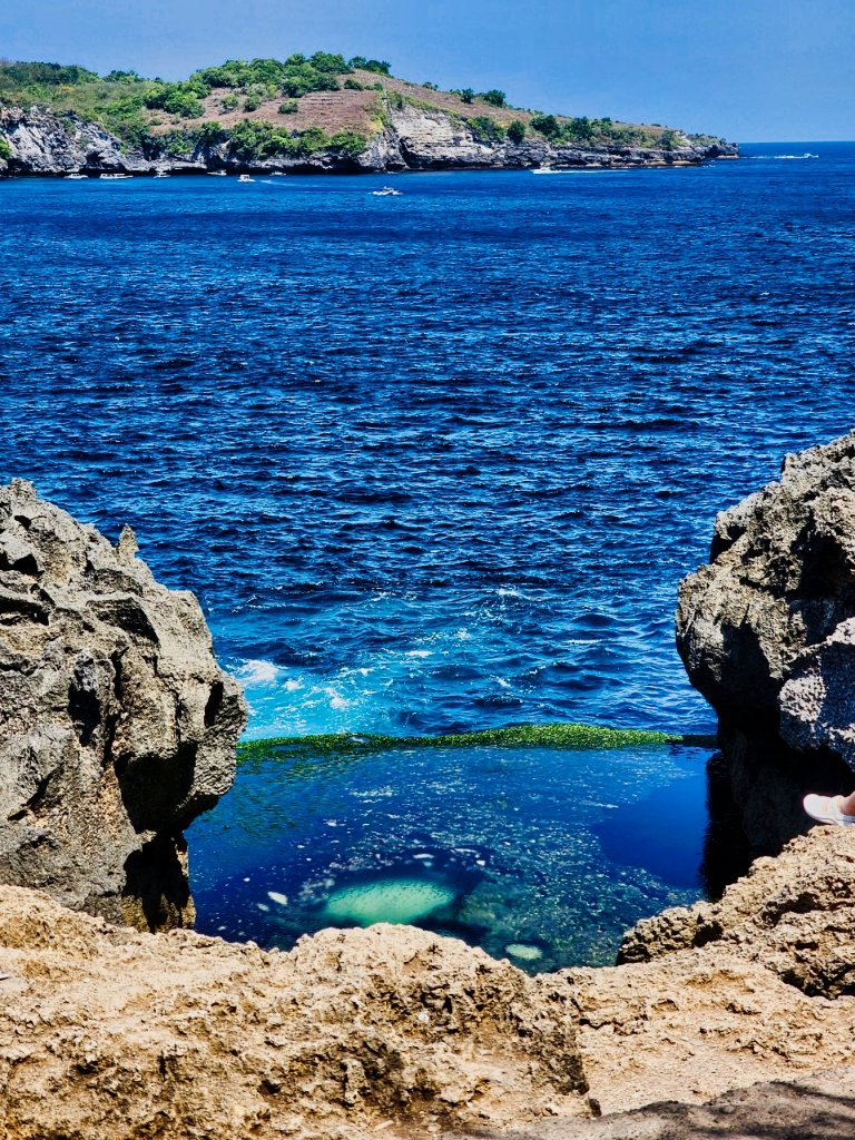 Rocky coastal cove with crystal turquoise water, limestone cliffs and lush green vegetation