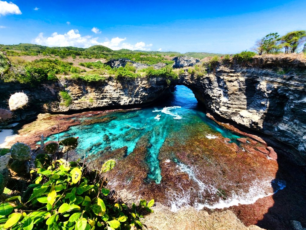 Dramatic rock arch formation with turquoise reef waters, tropical landscape with natural arch