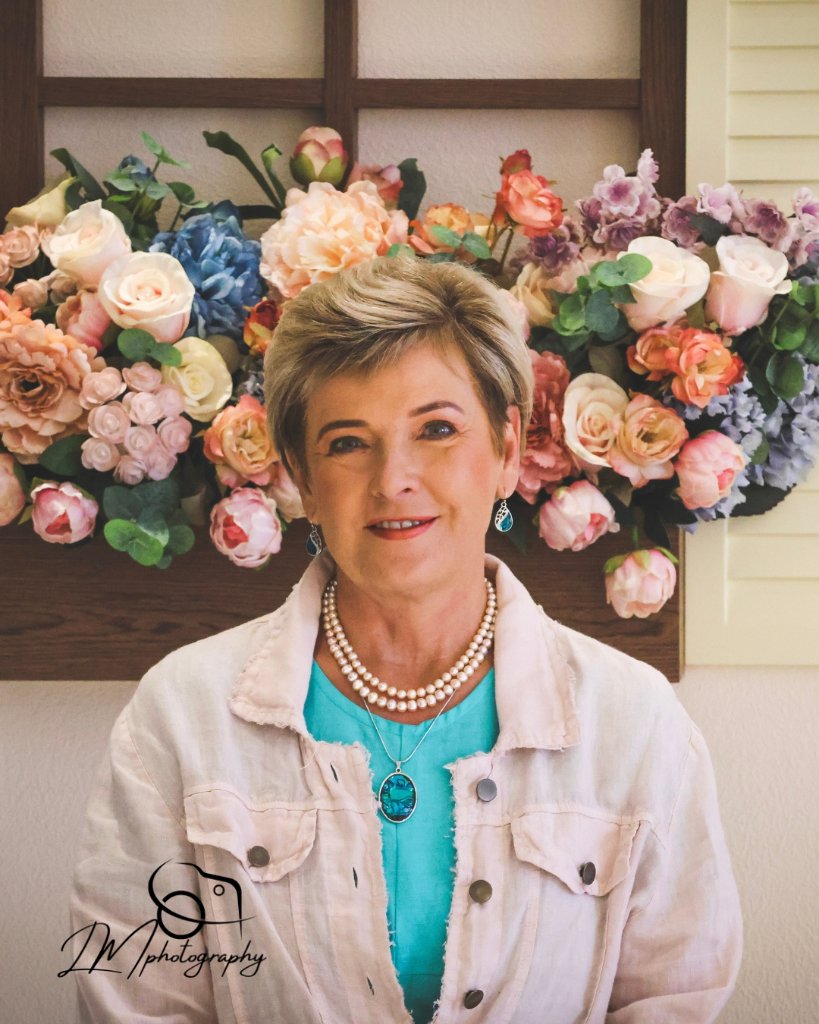 Woman posed in front of colorful floral arrangement backdrop