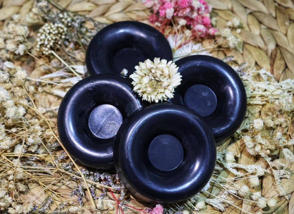 Black charcoal donut soap bars with dried flowers commercial product photography