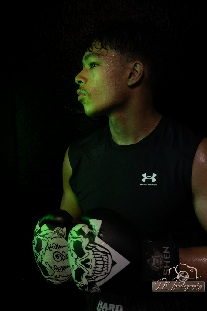 Young male boxer in profile with skull gloves and green edge lighting
