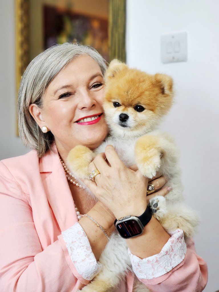 Woman in pink blazer holding Pomeranian puppy portrait