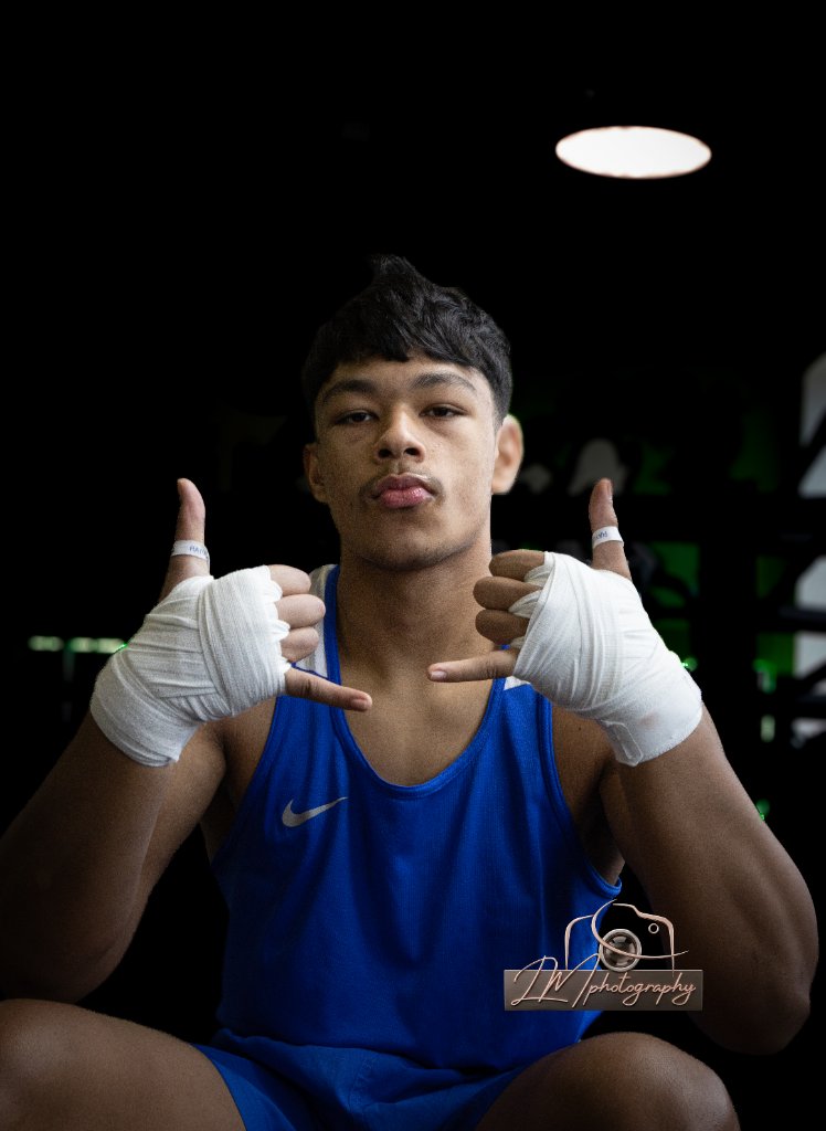 Boxer making shaka gesture with hand wraps against black background