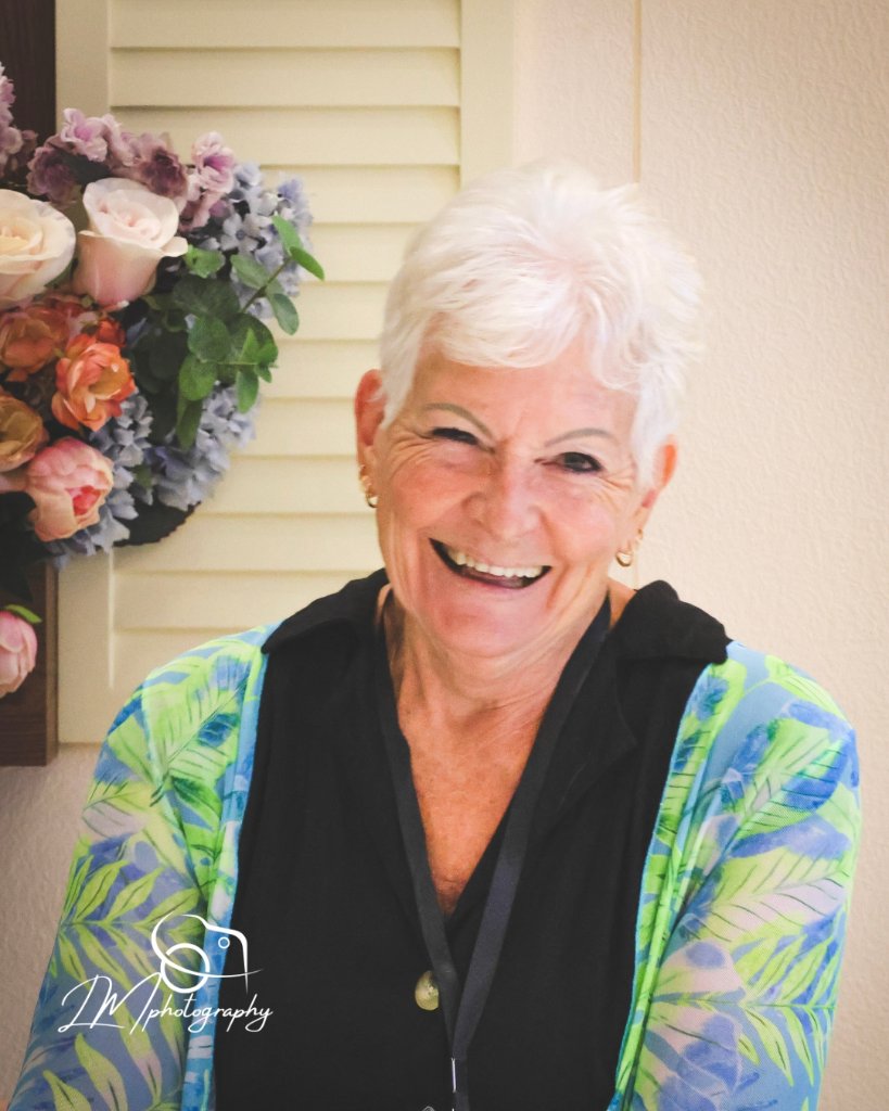 Woman smiling in front of colorful floral wall display