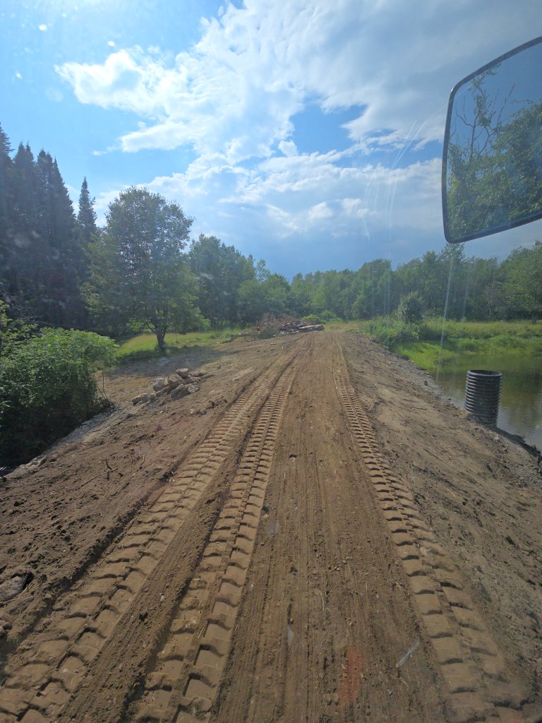 Dam top regraded and compacted — new standpipe overflow visible at right, pond beginning to refill