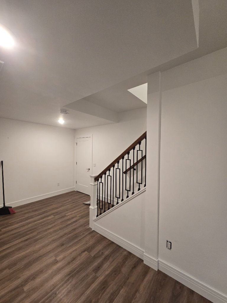 Finished Lower Level — Clean open space with updated staircase and fresh drywall