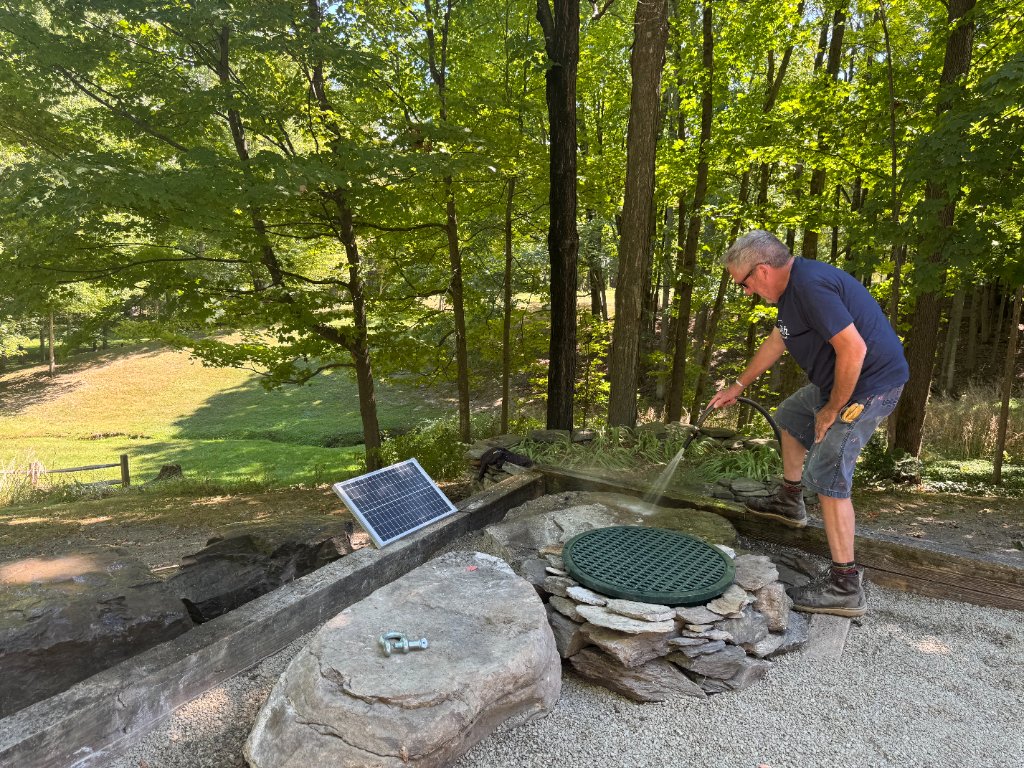 Solar-powered water feature installation — boulder placement and fountain finishing