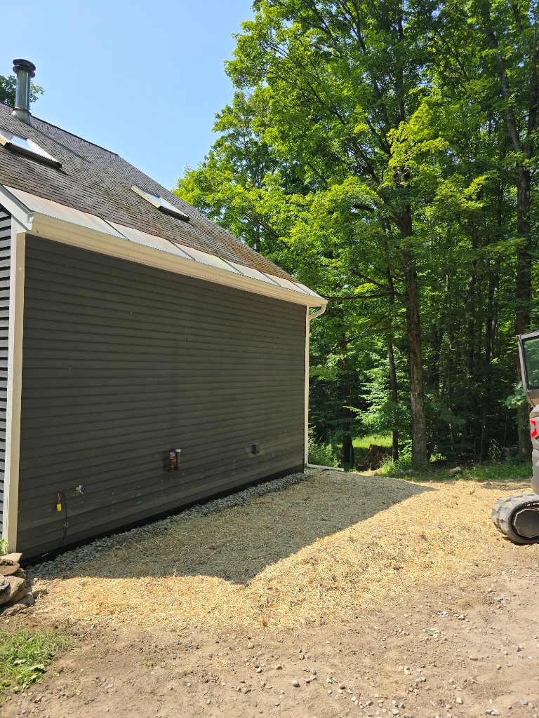 Completed Vermont wood foundation repair with stone curtain drain and regraded terrain