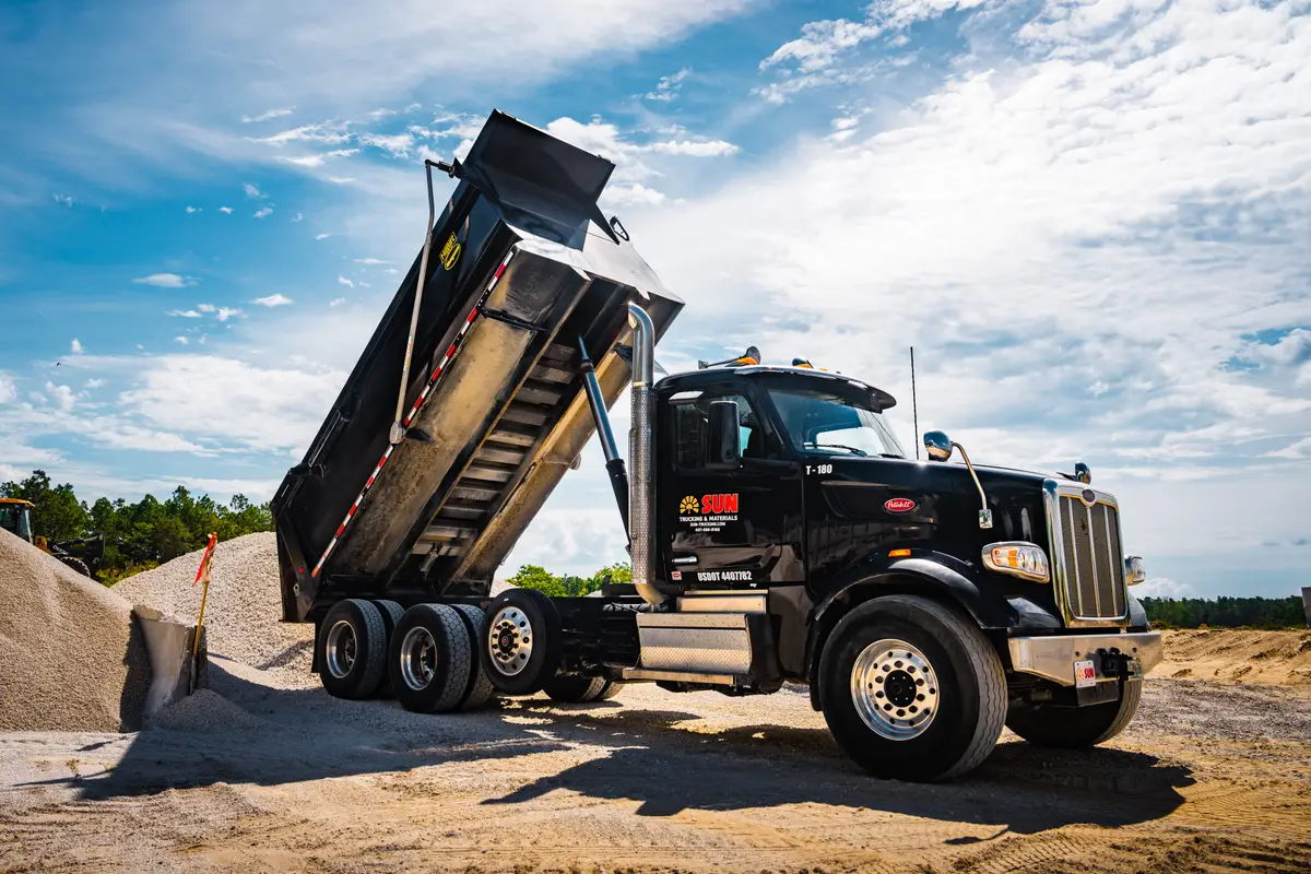 Dump truck raising its bed to unload crushed rock at the yard
