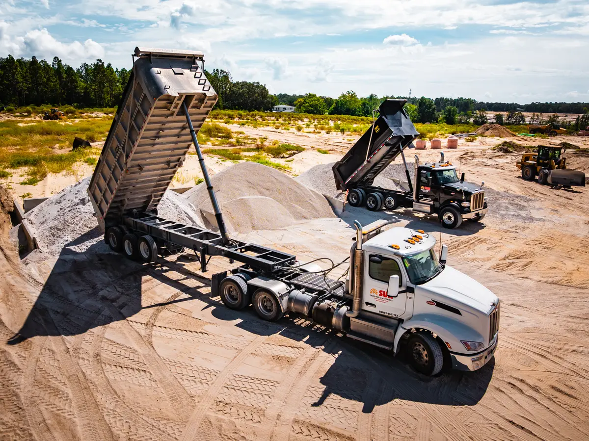 Dump trucks and excavator working a gravel yard