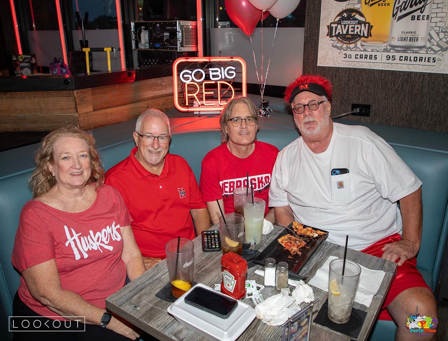 Huskers fans at a booth under the GO BIG RED neon sign at Lookout Tavern