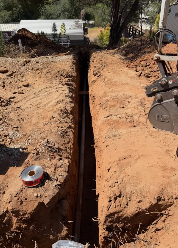 Excavator bucket working an underground trenching job with conduit installation in Eucalyptus Hills, CA