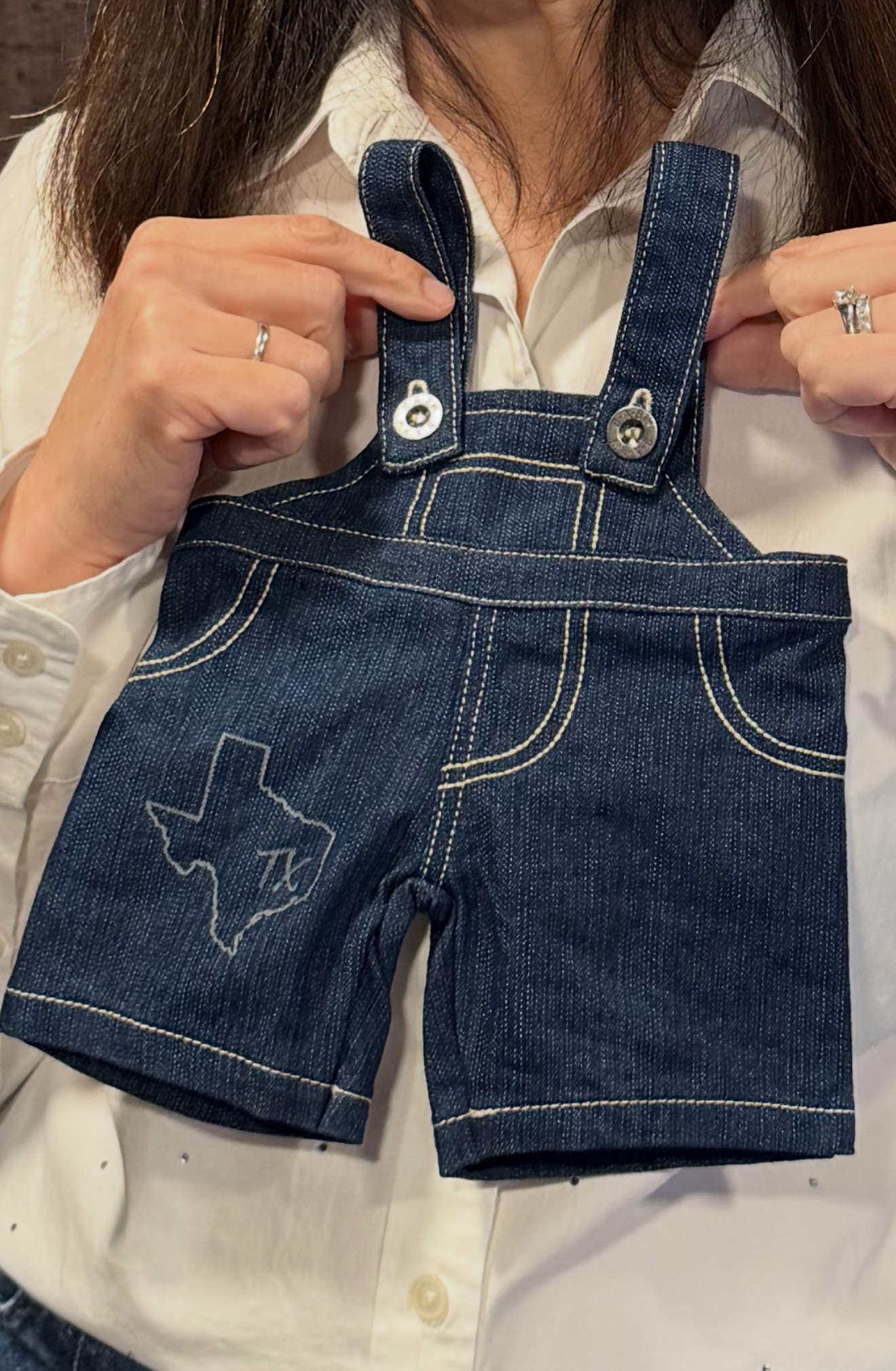 A guest holds up miniature denim overalls with a custom embroidered Texas outline, an example of an in-store activation idea
