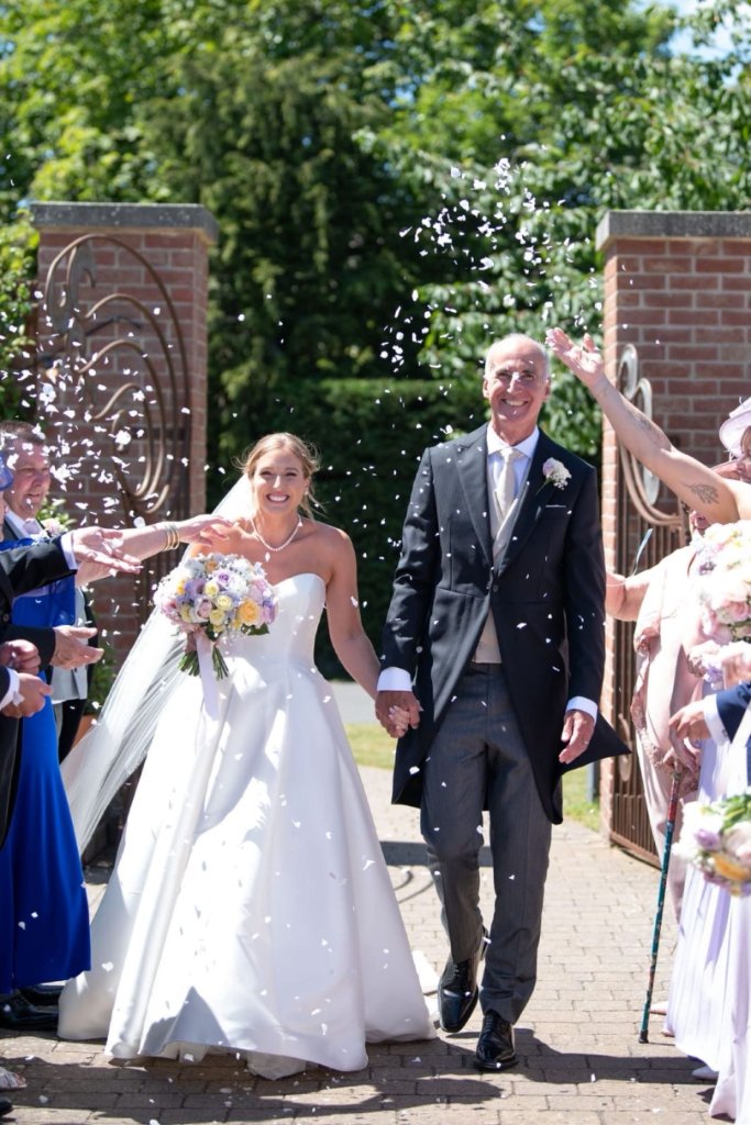 Bride walking with her father through confetti at their wedding