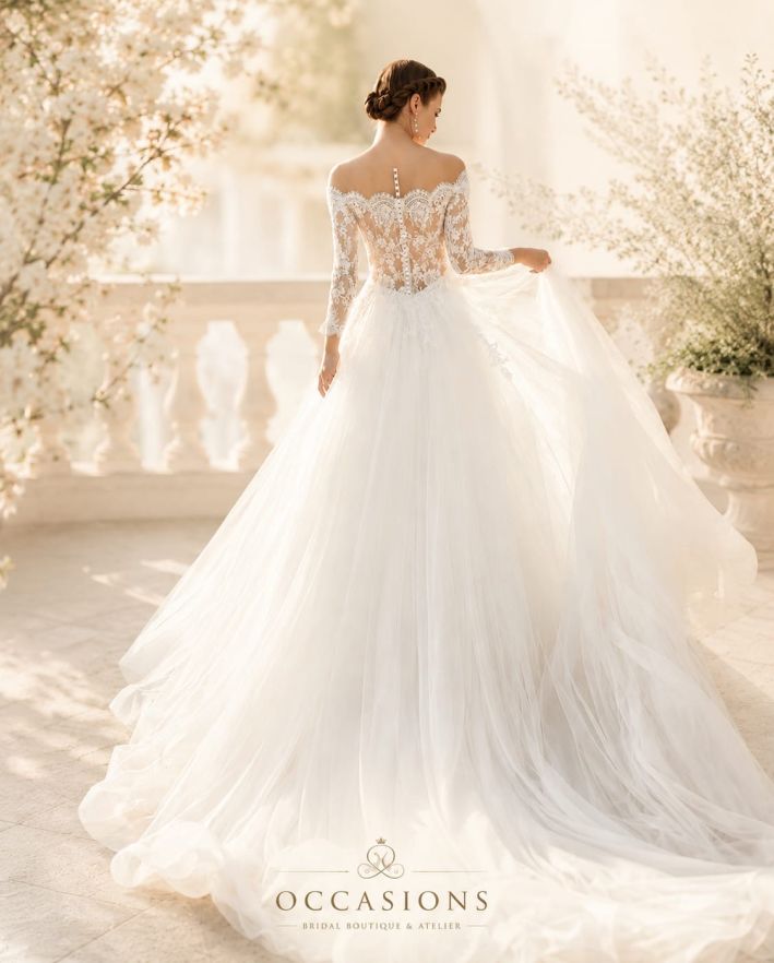 Bride in an off-the-shoulder gown with sheer lace sleeves on a sunlit terrace