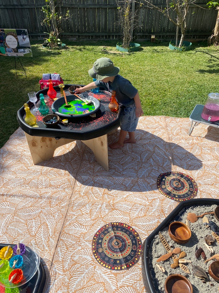 Child playing at an outdoor sensory tray setup