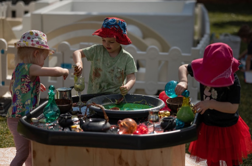 Three children playing together at a sensory tuff tray