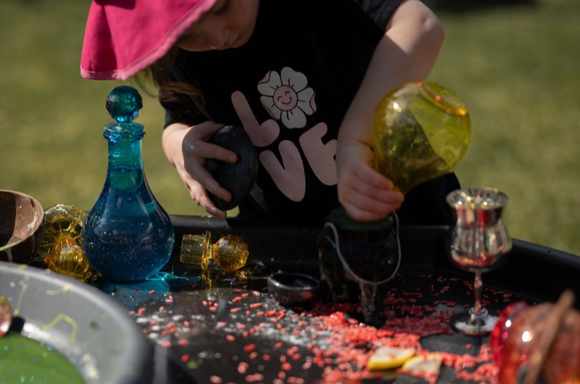 Child pouring potion into a cauldron at a tuff tray