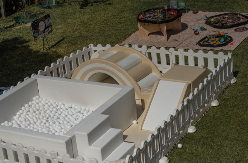 Outdoor soft play setup with white ball pit, rainbow climber and tuff tray