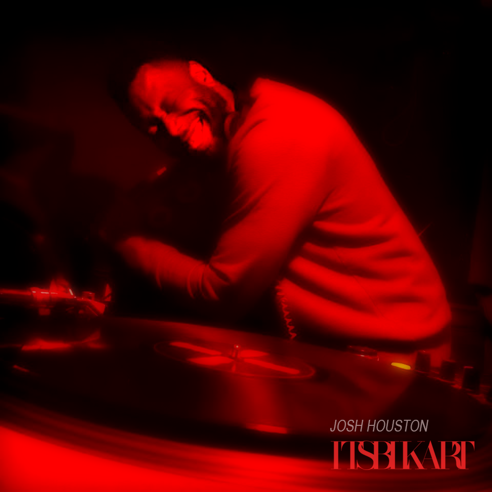 Josh Houston DJing in profile, bathed in red light, leaning over a turntable.