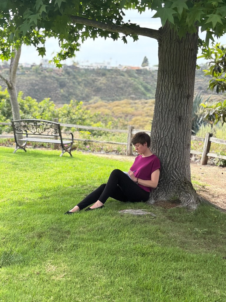 Brittany Olson journaling outdoors beneath a tree