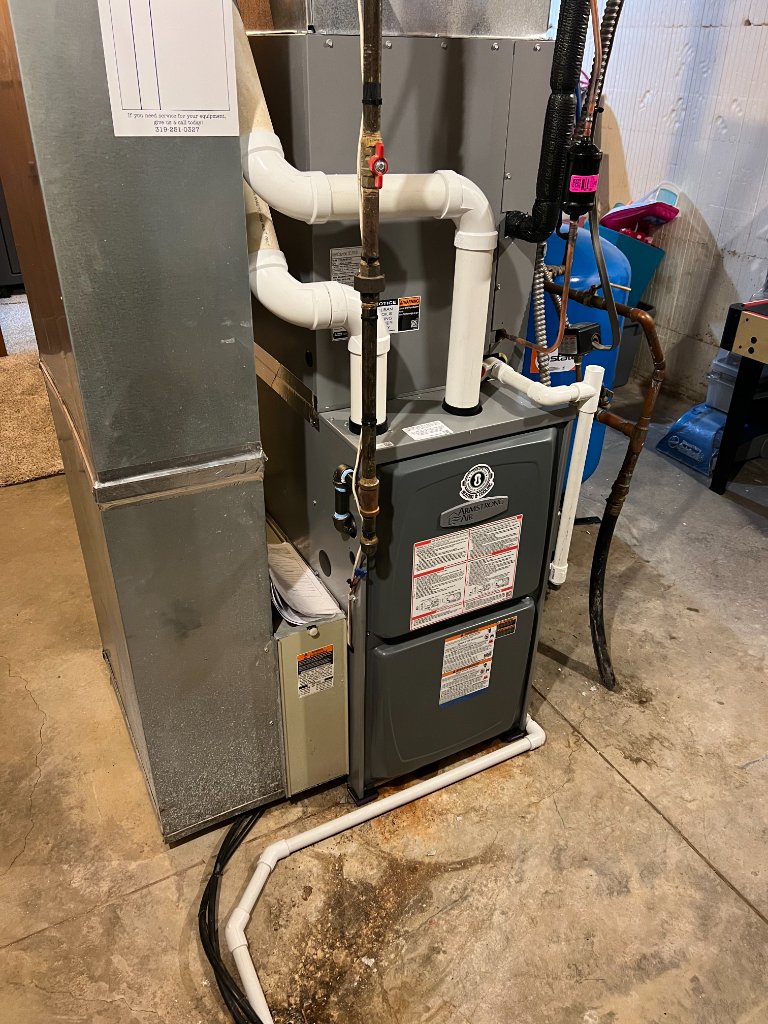 Another view of a different furnace setup located indoors with visible plumbing connections.