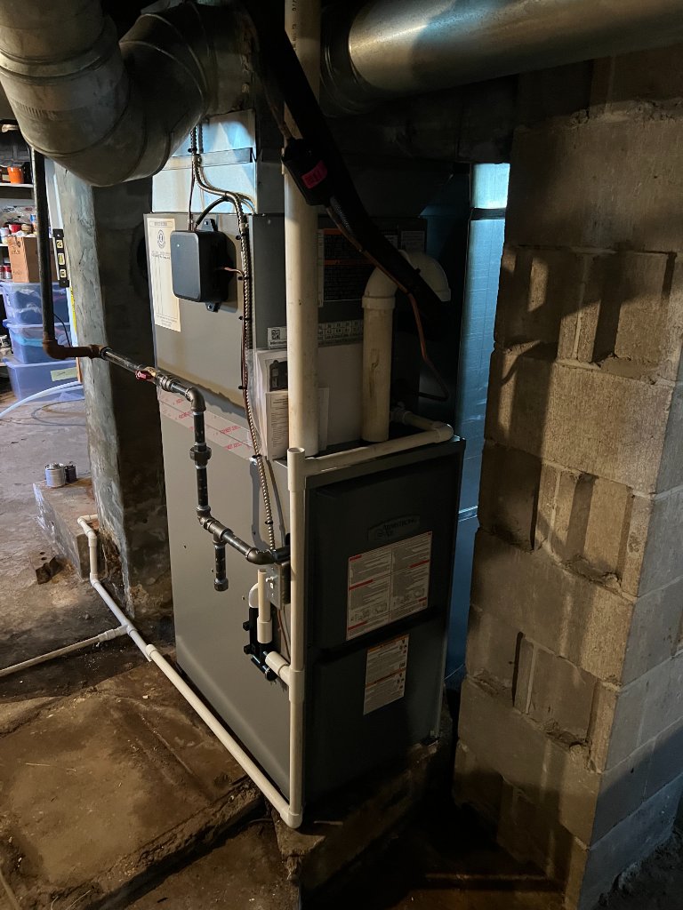 A close view of a furnace indicating its installation in a basement area with visible connections and ductwork.
