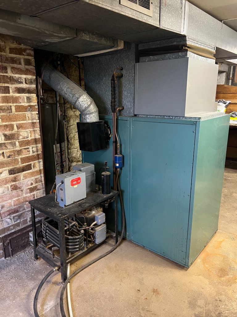 The image shows a furnace with an adjacent compressor unit, highlighting the integration of heating and cooling systems.