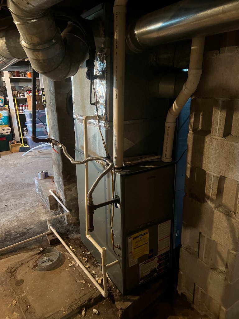 This image depicts a furnace unit, recognizable by its indoor installation with ductwork.
