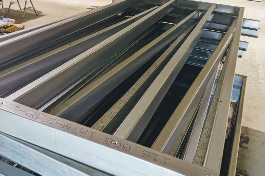 Light gauge steel panels stacked flat at the factory — close-up of studs and tracks