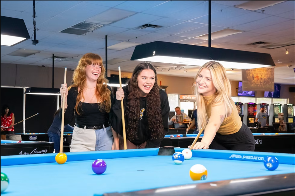 Friends playing billiards on a Predator table