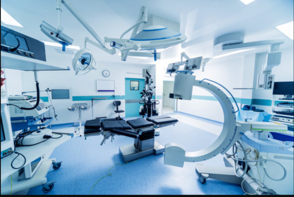 Modern operating room with surgical table, C-arm imaging unit, and medical monitors