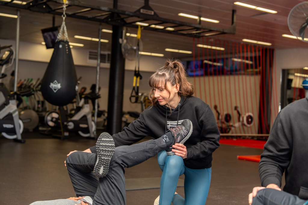 Sara guiding a client through a stretch — hands-on coaching
