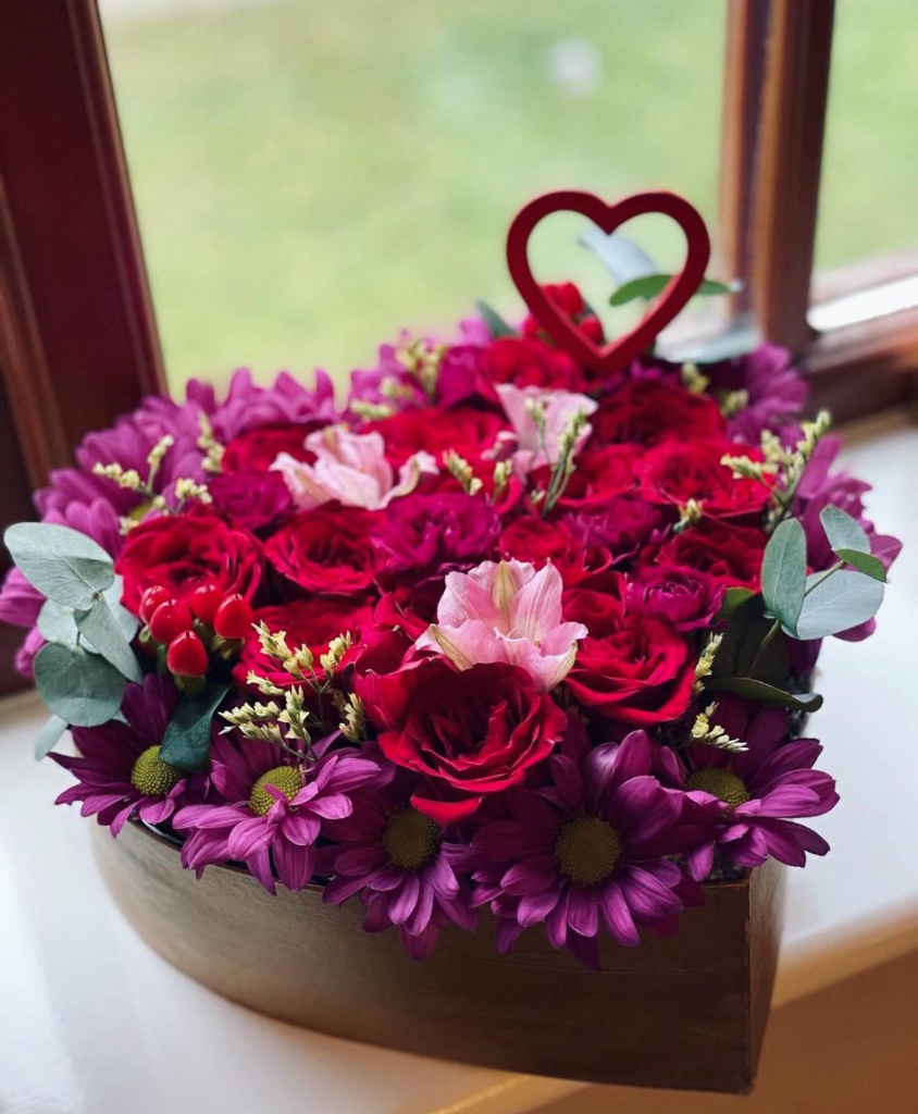 Heart-shaped red and purple flower box with heart topper by Kalea Arrangements