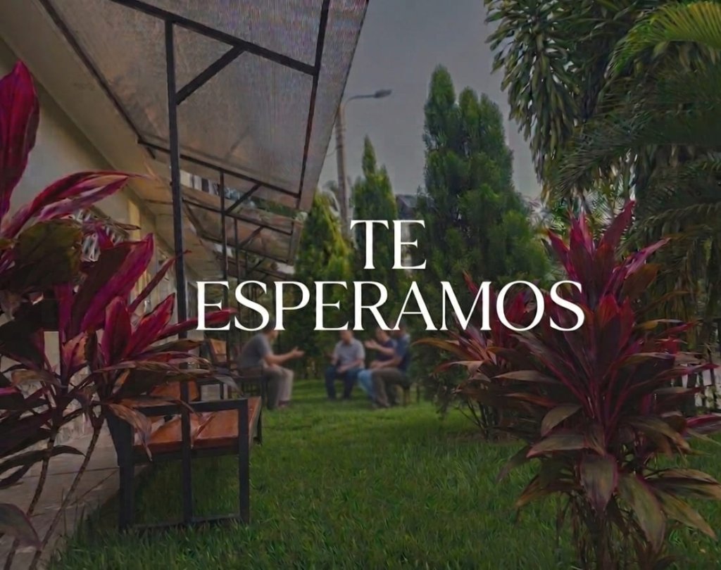 Área de descanso con techo, bancas y jardín tropical — Te Esperamos