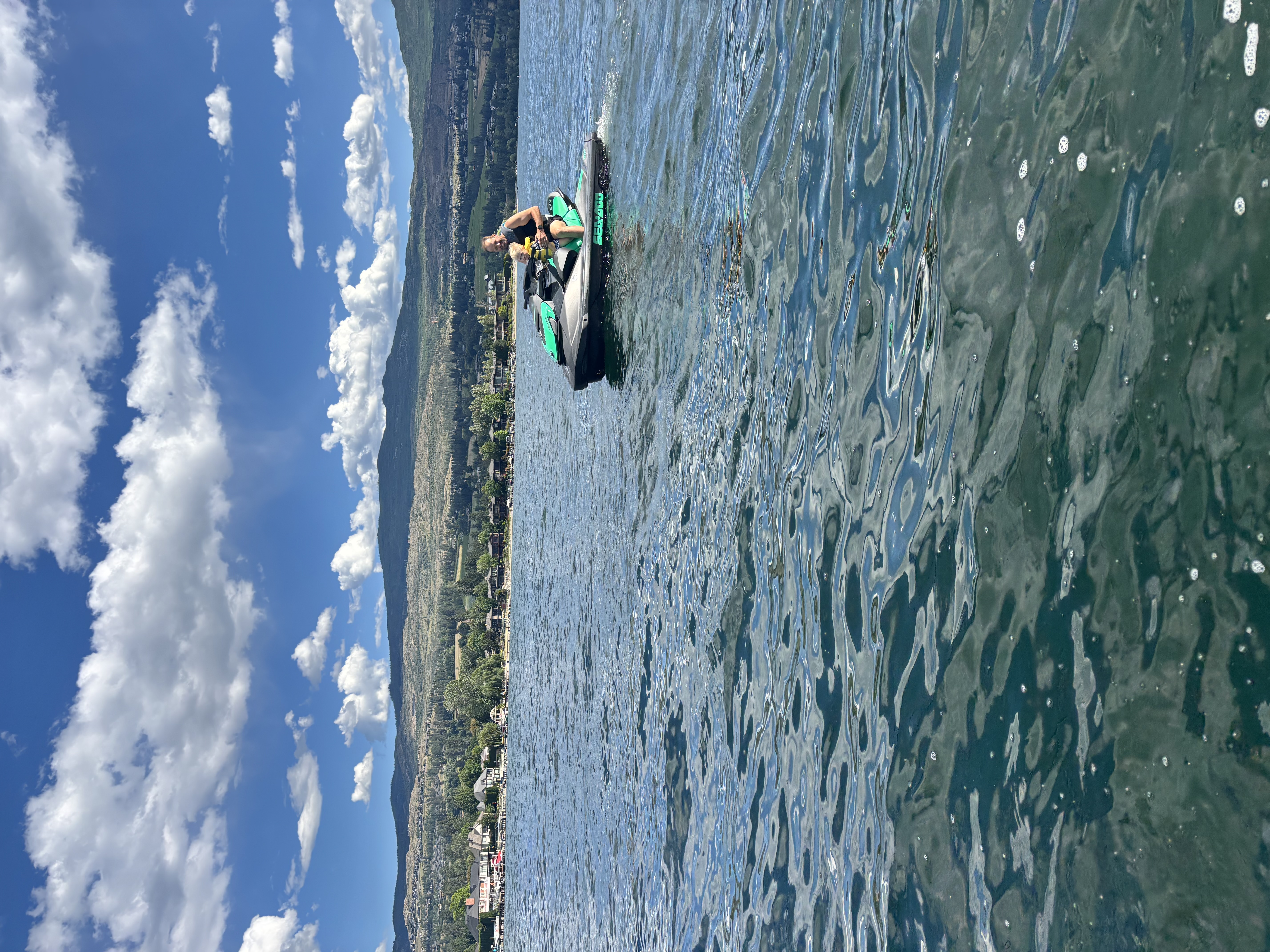 A Sea-Doo jet ski riding across Okanagan Lake with a child passenger