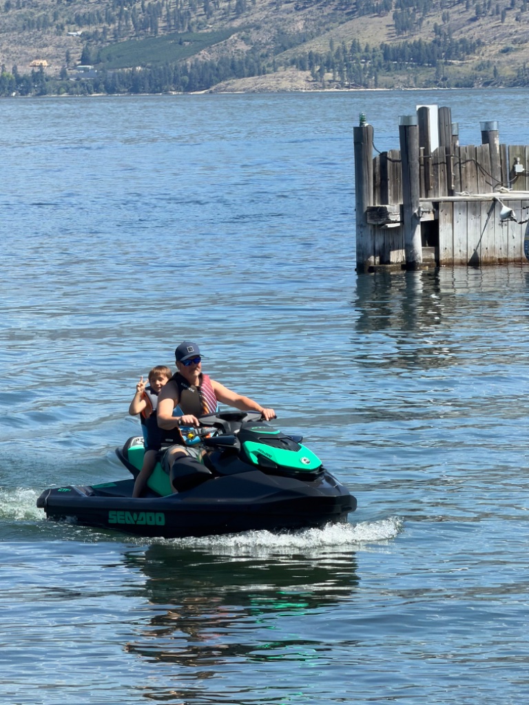 Man and child enjoying a Sea-Doo ride near a dock in Kelowna
