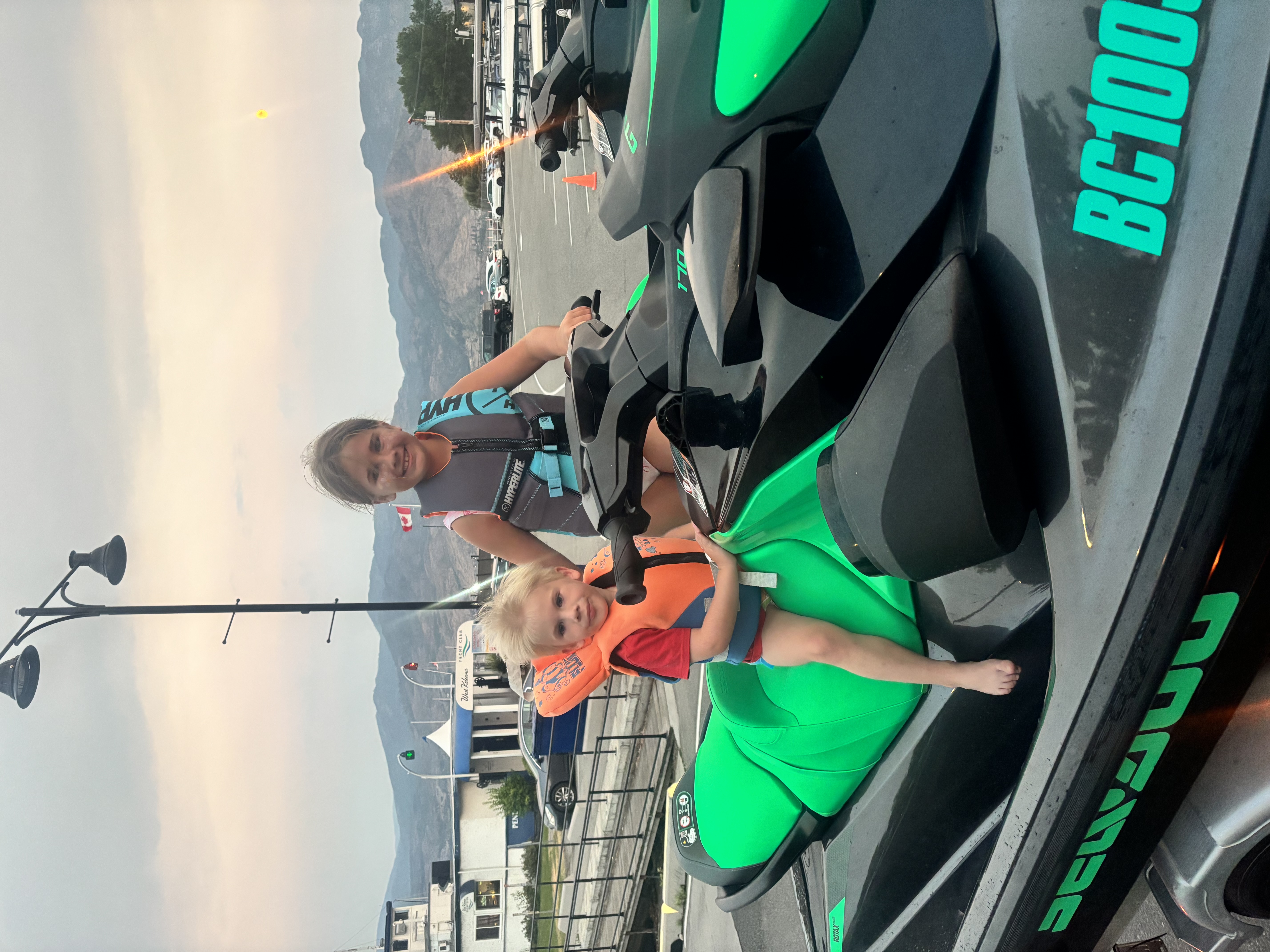 Two children seated on a Sea-Doo jet ski wearing fitted life jackets