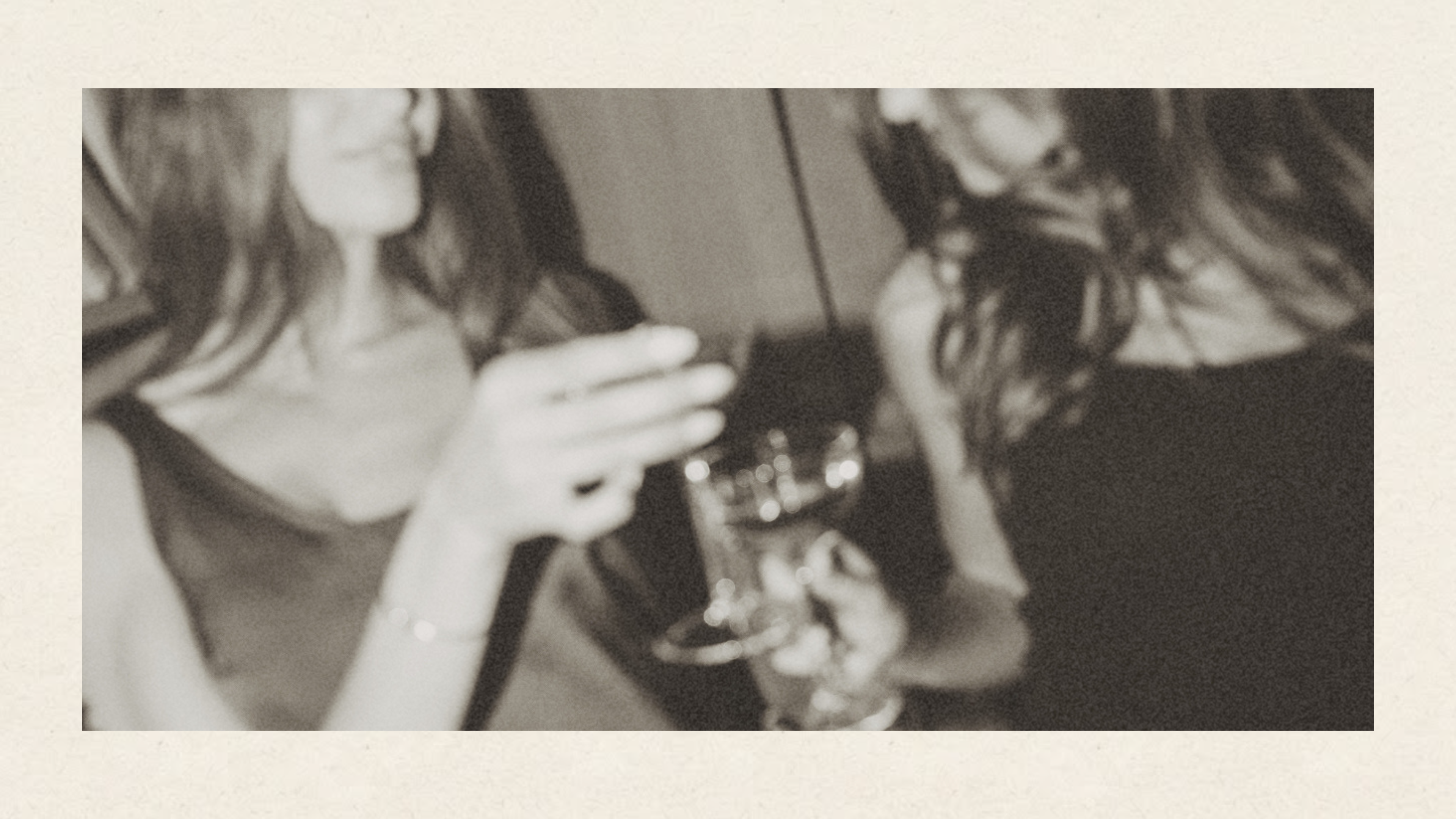 Two guests with drinks inside an Accomplice photobooth, vintage film-grain photo