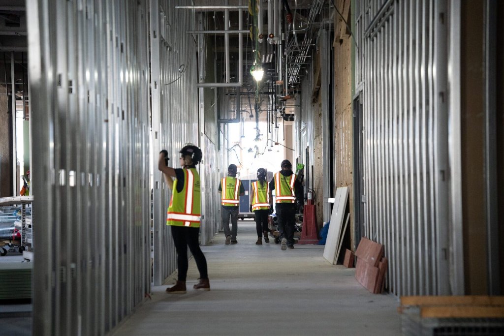 Construction workers in a narrow corridor with poor lighting conditions