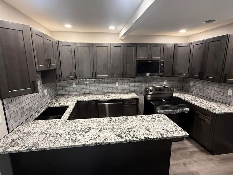 U-shaped kitchen with dark shaker cabinets, white granite countertops with black veining and grey subway tile, Schenectady