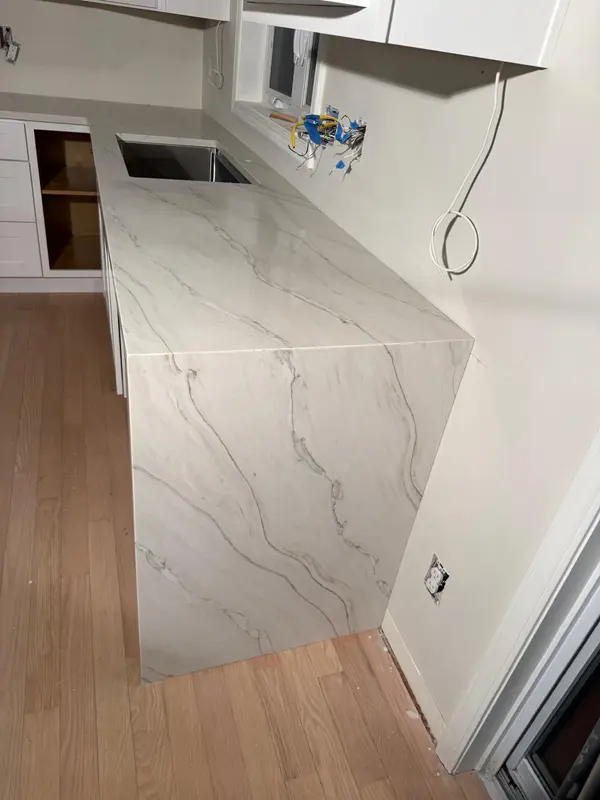 Waterfall-edge white stone countertop with grey veining and undermount stainless sink on light wood flooring, Schenectady