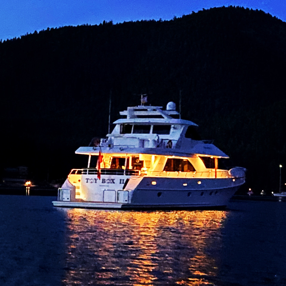 TOYBOX II illuminated at twilight — warm glow on still water