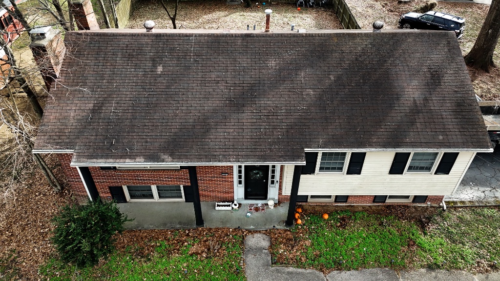 Storm-damaged residential roof with missing shingles and exposed decking