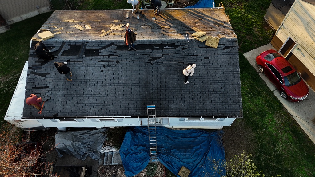 Roof with curled, cracked and missing asphalt shingles after storm damage
