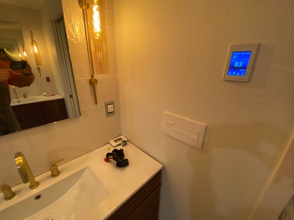 Smart thermostat and in-wall toilet flush panel — zellige tile, brass vanity detail