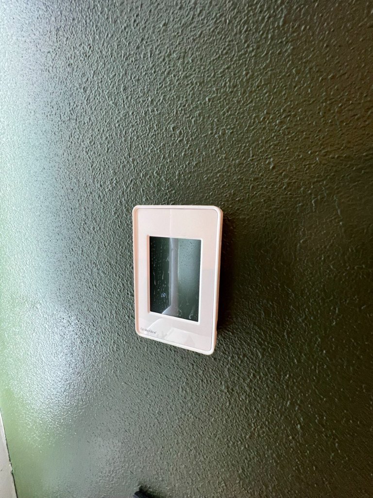 Smart home controller on textured forest green wall