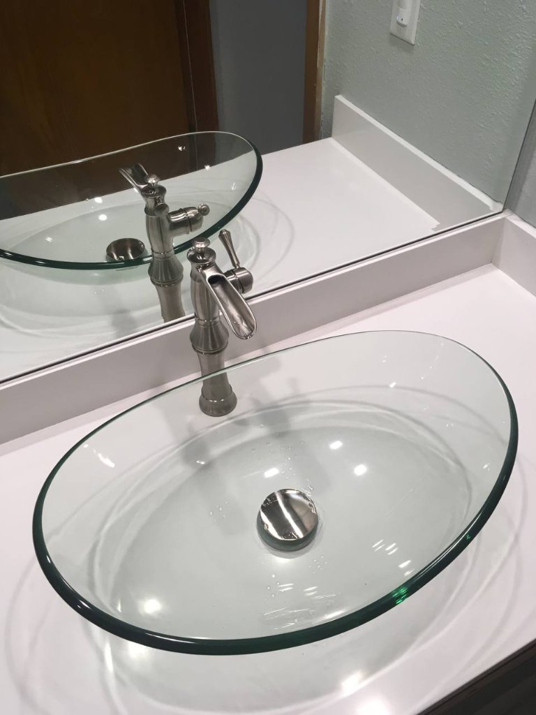 Close-up — clear glass oval vessel sink with brushed nickel bamboo faucet