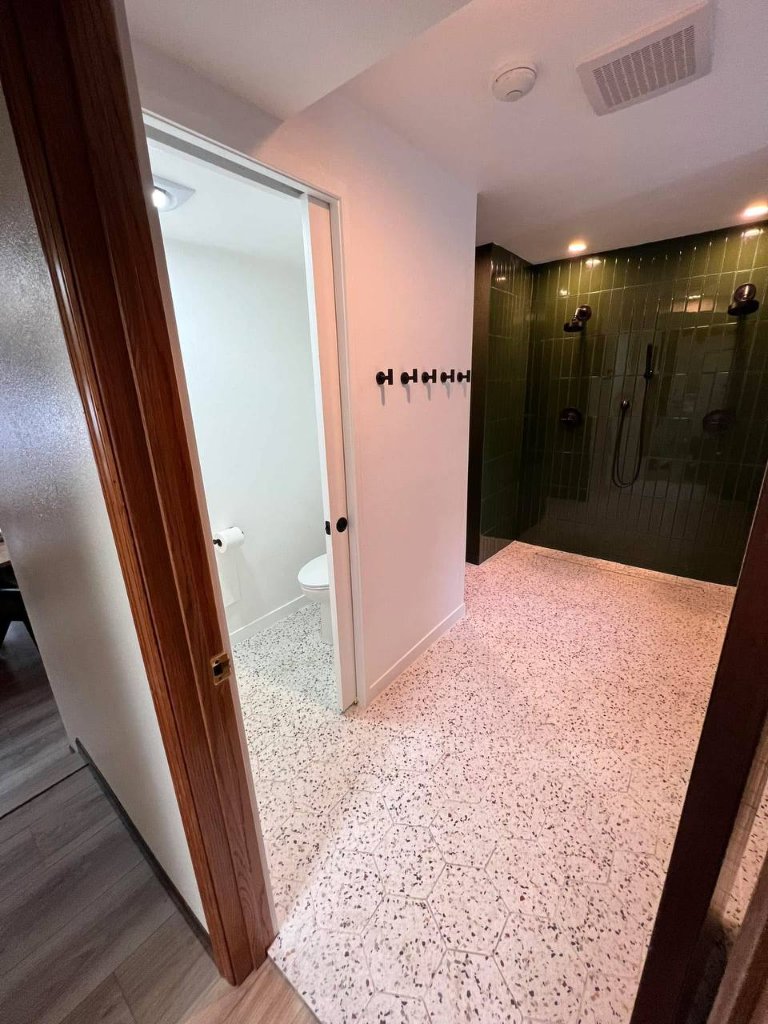 After — hallway view showing private toilet room and green shower suite